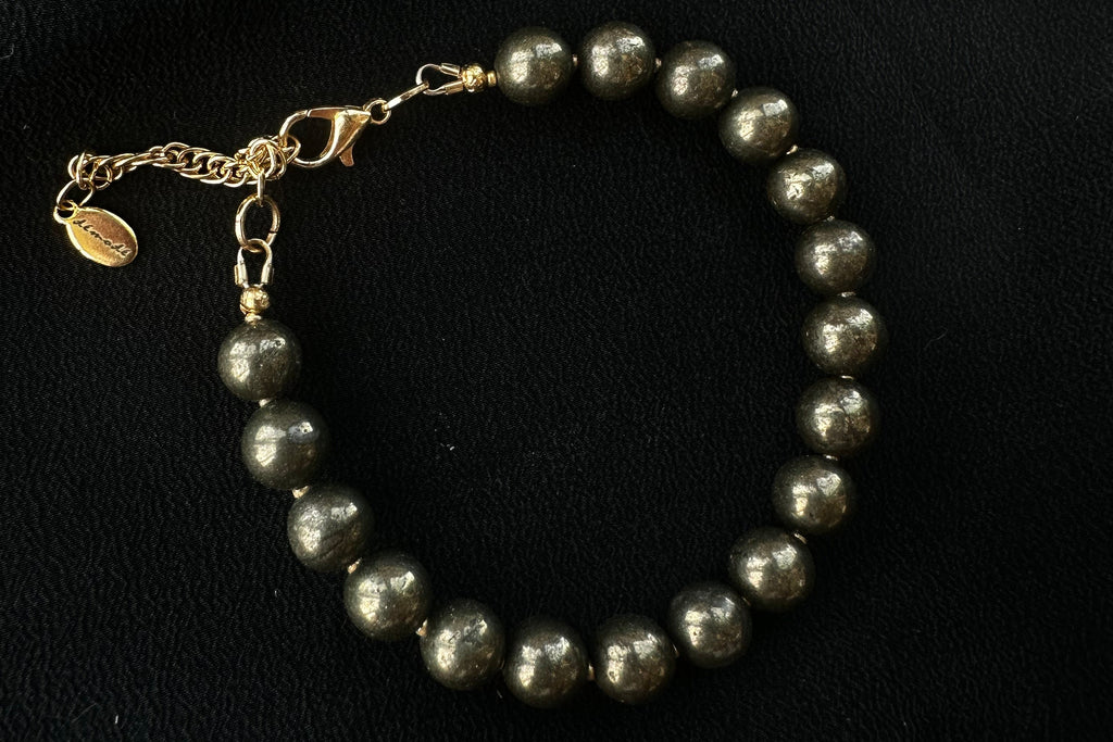 Golden pyrite beaded bracelet with a gold chain on a black background