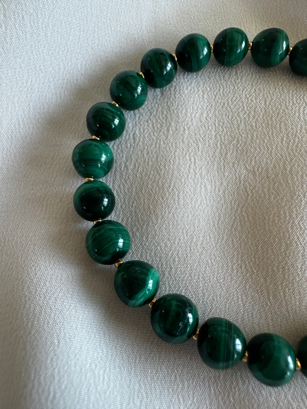 Green beaded necklace on a textured white surface