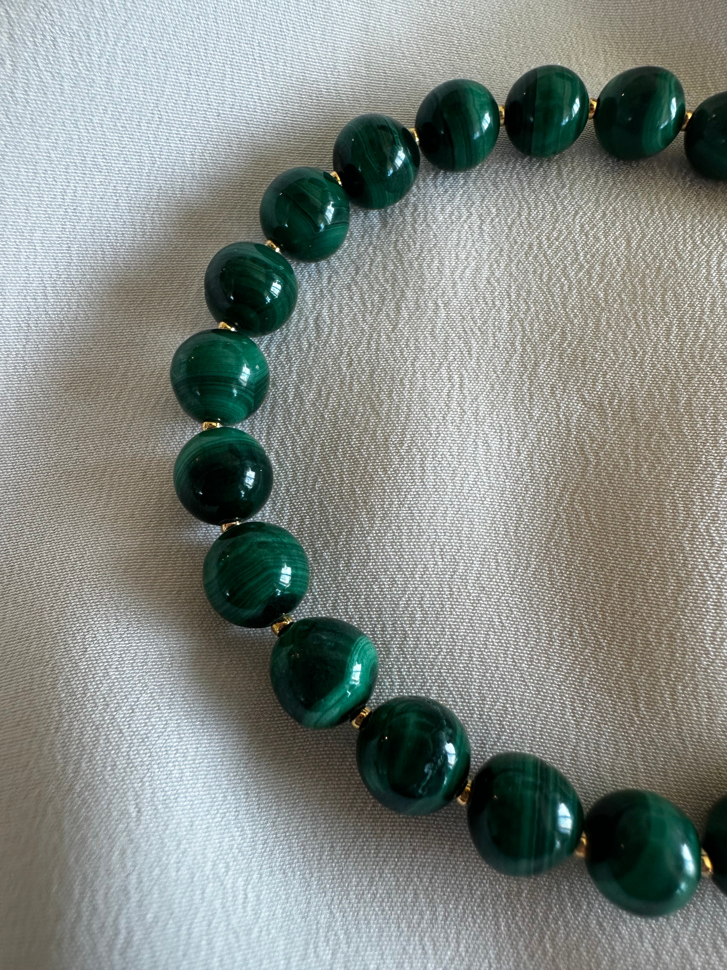 Green beaded necklace on a textured white surface