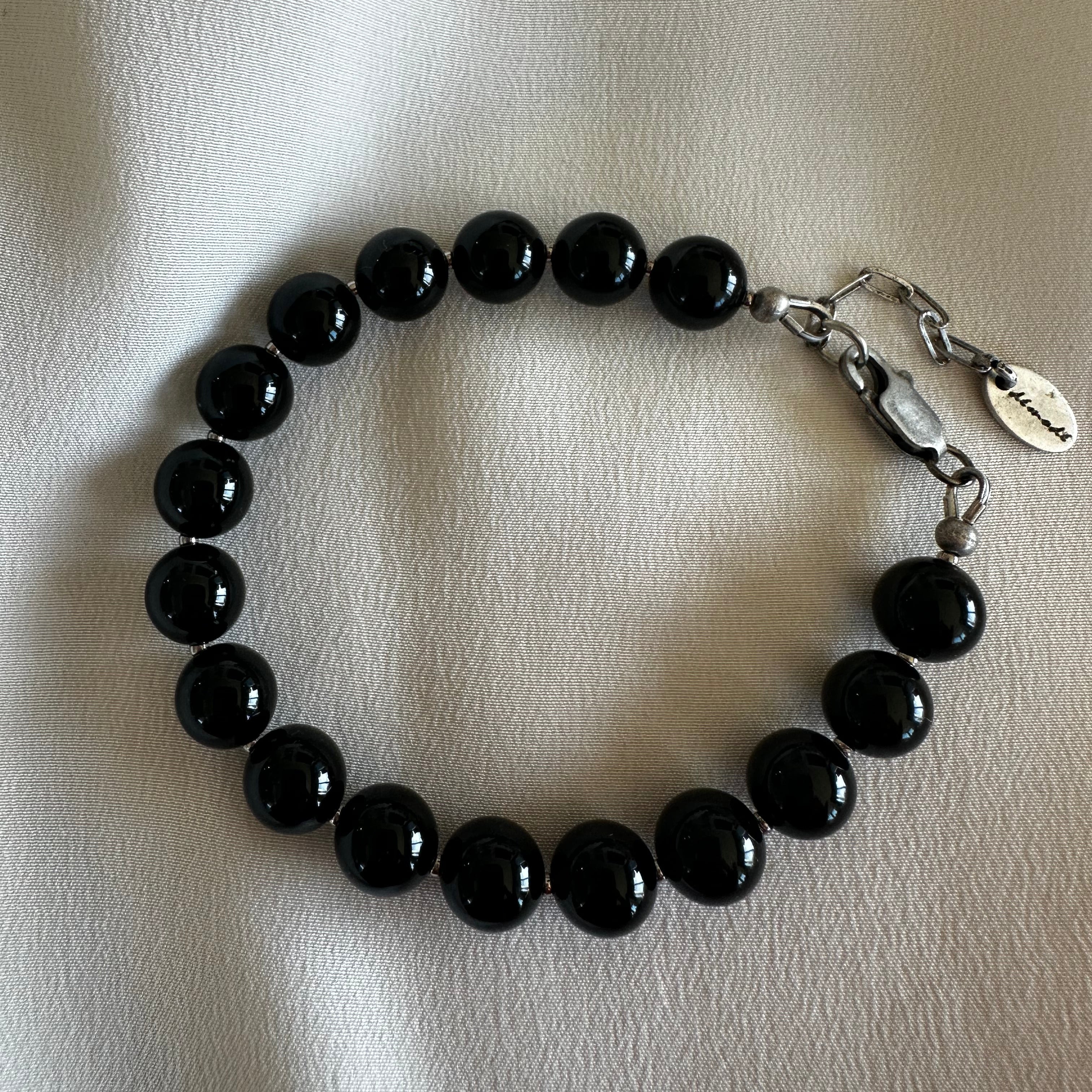 Black spinel beaded bracelet with a silver clasp on a light background