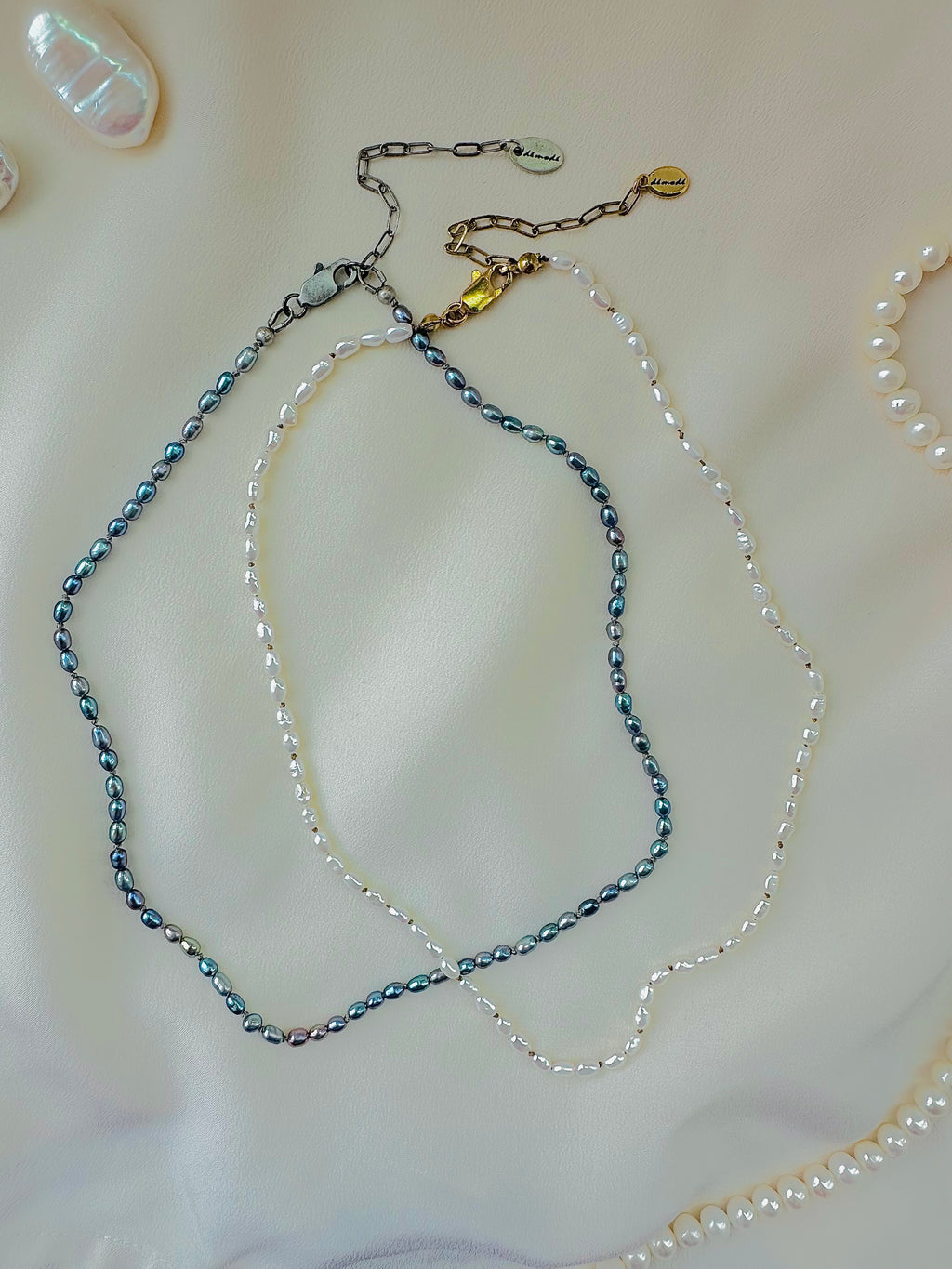 Two pearl necklaces on a light pink surface
