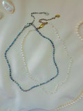 Two pearl necklaces on a light pink surface