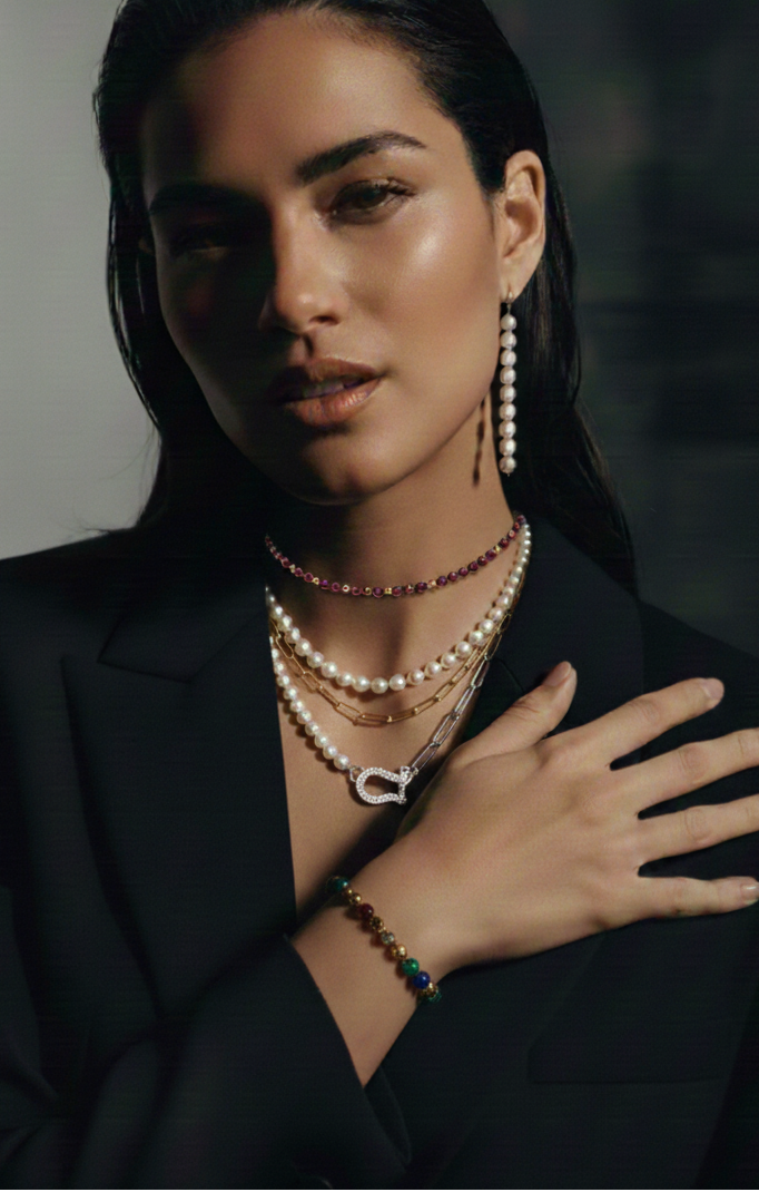 Woman wearing multiple necklaces and a bracelet with a blurred background