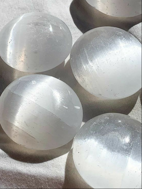 Clear selenite crystal balls on a textured surface